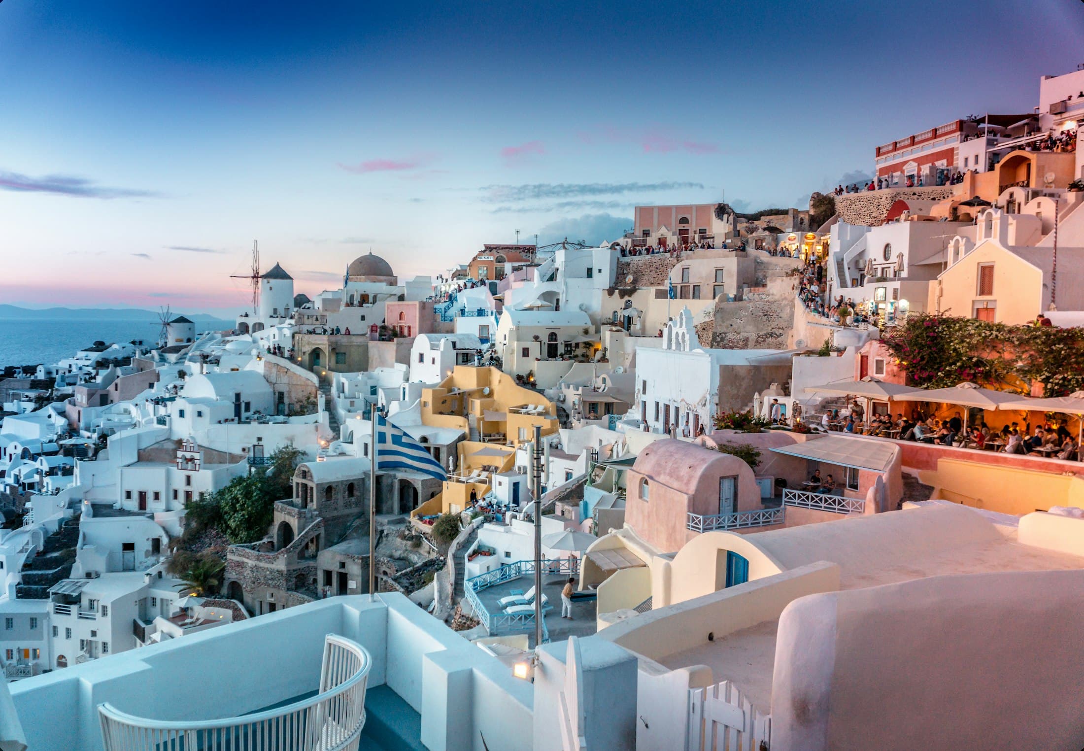 Whitewashed coastal buildings above the sea at dusk