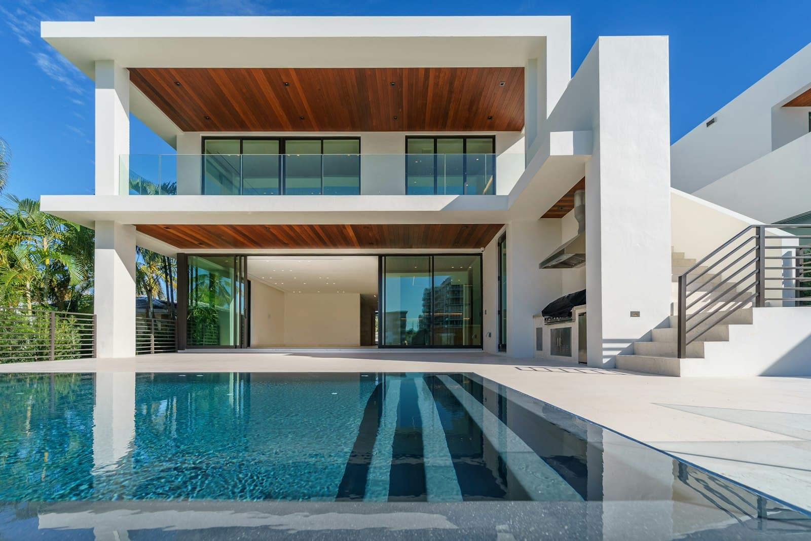 Modern waterside home with a pool and palm trees